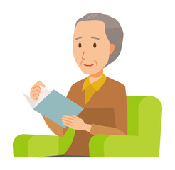 An elderly man wearing brown clothes is reading on a sofa