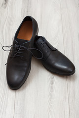 Pair of black leather men's shoes on grey wooden background