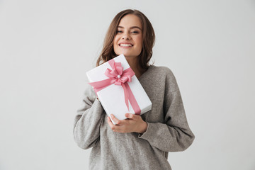 Smiling brunette woman in sweater holding gift box