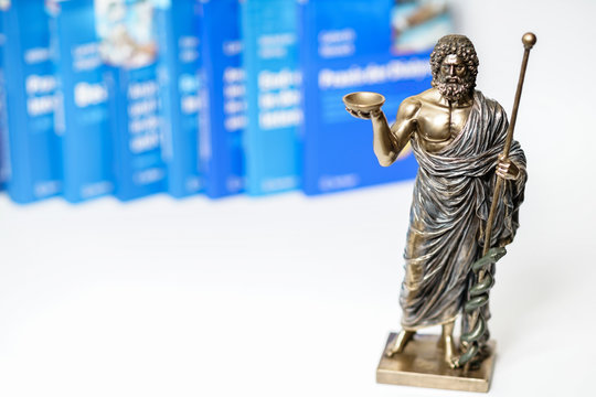 Hippocrates statue on blured medical books and stethoscope background