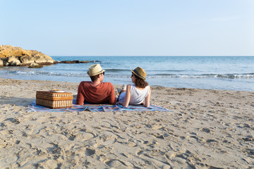 Pareja joven mirándose con complicidad mientras cenan en una playa del mar Mediterráneo