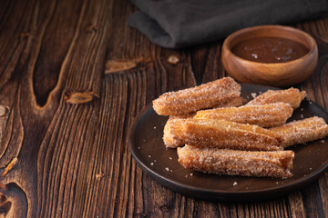 Traditional churros Spanish homemade sweet dessert pastry food on vintage wooden table background.