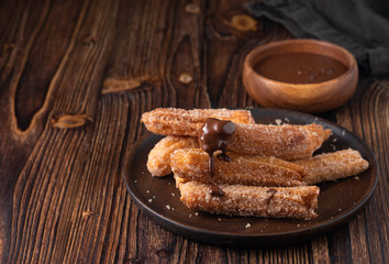 Traditional churros Spanish homemade sweet dessert pastry food on vintage wooden table background.