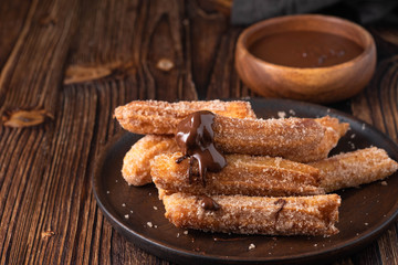 Traditional churros Spanish homemade sweet dessert pastry food on vintage wooden table background.