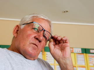 Senior mit weißen Haaren setzt sich seine Brille auf