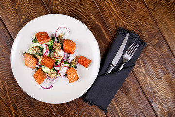Grilled salmon with radish and spinach, served on white plate. View from above, top studio shot