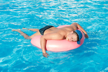 drunk resting guy on the inflatable circle in the swimming pool of the hotel