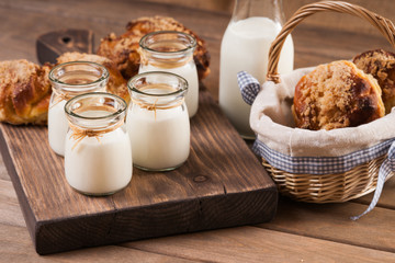 Bread buns, jars with milk on a cutting board 