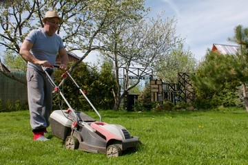 man mowing grass on a garden plot