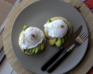 Avocado and poached eggs on crumpets with jalapeno and cheddar sauce with sprinkle of salt and pepper. Shot from top, natural light, close up and Selective focus on egg poach