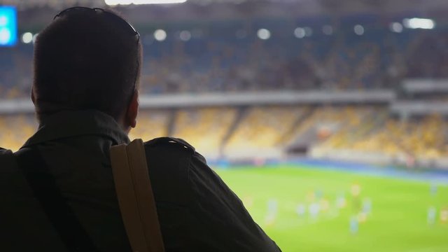 Male soccer fan watching game, world championship. Players running on field. Football game in progress, 4K