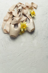 Pointe ballet shoes, Yellow Flower Narcissus on a light stone background. The concept of ballroom dancing