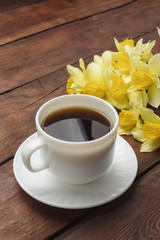 Cup of coffee, Spring flower Narcissus on a dark wooden background