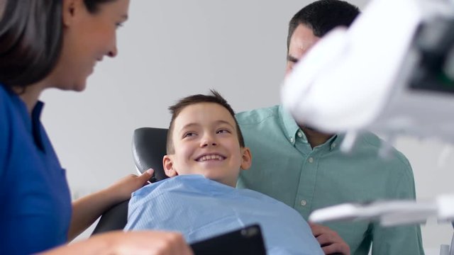 medicine, dentistry and healthcare concept - father and son visiting dentist at dental clinic
