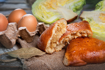 Patties with cabbage on a dark wooden table top view. Advertising still life from baking.