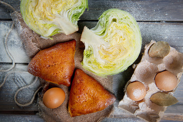 Patties with cabbage on a dark wooden table top view. Advertising still life from baking.