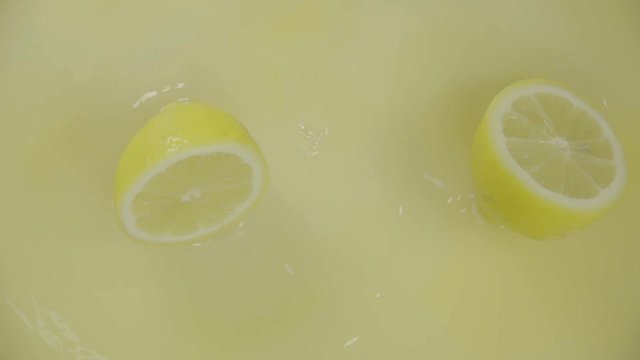 Fresh Lemon falling in juice and slices with splashes