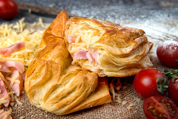 Buns with ham and cheese made of puff pastry on a dark wooden table. Advertising still life from baking....