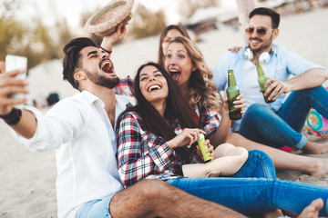 Group of young friends laughing and drinking beer