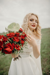 Beautiful bouquet of red roses held by a bride. Selective focus. Wedding flora. Elegant dress.