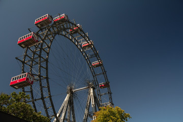 Retro vintage red cabins of famous old ferris wheel at Prater amusement fun attraction park Vienna...
