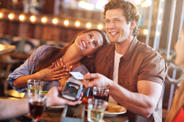 Cute couple on a date at the cafe paying by credit card