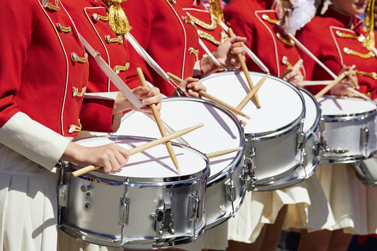 Closeup of group of girls of fans in red military uniform with drums.