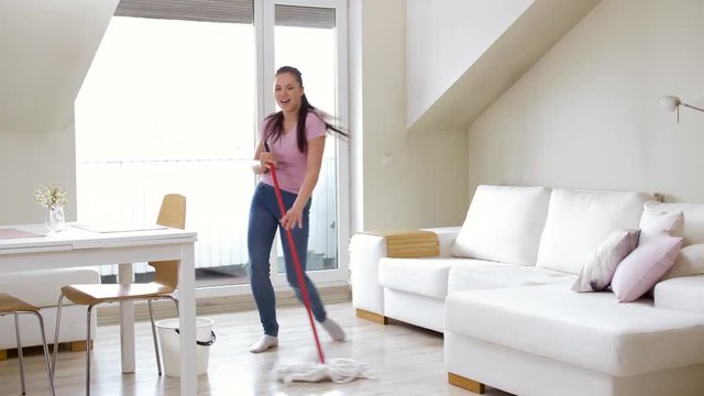 people, housework and housekeeping concept - happy woman or housewife with mop cleaning floor and dancing at home