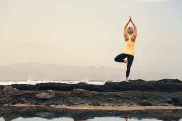 Yoga girl meditating and relaxing in yoga pose, ocean view