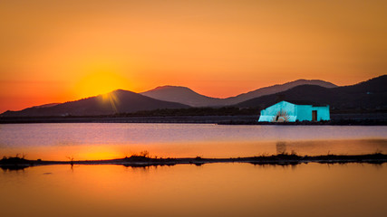 warm sunset in the Balearic salinas with salt house in blue