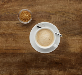 Obraz premium A cappuccino coffee, shot on a wooden worktop, with brown sugar.