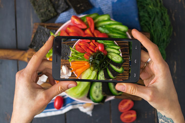 Phone photography of food. Woman hands take photo of lunch with smartphone for social media. Buddha bowl. Raw vegan vegetarian healthy dinner 