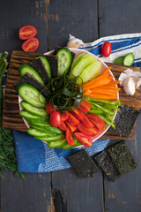 Raw vegan buddha bowl with fresh vegetables on wooden board. Cucumber, tomatoes, carrot, seaweed, radish, capsicum, flax flatbread. Vegetarian healthy food