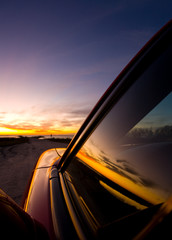 Fototapeta premium sunrise on the coast with car silhouette and reflections of sunrise on windows