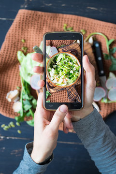 Phone photography of food. Woman hands take photo of lunch with smartphone for social media. Fresh vegetables salad. Raw vegan vegetarian healthy dinner 