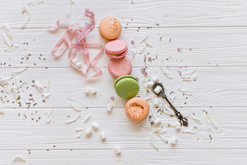 A flat lay of a colorful macarons , spoon on the white texture background