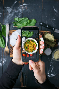 Phone photography of food. Woman hands take photo of lunch with smartphone for social media. Quinoa salad. Raw vegan vegetarian healthy dinner 