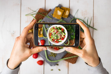 Phone photography of food. Woman hands take photo of lunch with smartphone for social media. Fresh vegetables salad. Raw vegan vegetarian healthy dinner 