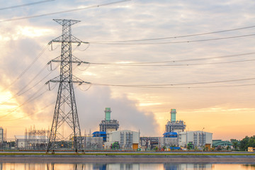 The sun is rising behind a power plant.