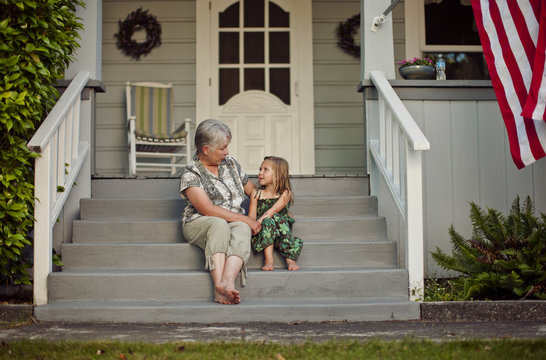 Grandmother talking with her granddaughter while sitting on steps