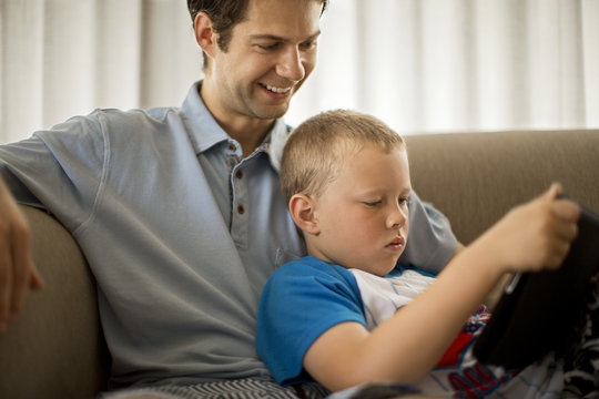 Smiling young man and boy looking at a digital tablet.