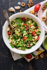 Fresh vegetable salad in bowl with avocado, spinach, cabbage, cucumbers, tomatoes, olive oil. Mediterranean food served with avocado dip and flatbreads, Raw vegan vegetarian healthy food