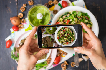 Phone photography of food for social networks. Smartphone photo of fresh vegetables salad with cucumbers, mushrooms, avocado dip sauce and greens.Raw vegan vegetarian healthy food