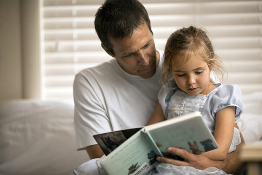 Father and daughter reading story book at home