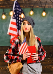 College students in library against composite image of USA national flag. English female student with the American flag at the background.