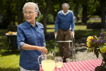 Smiling senior woman stirring lemonade at a picnic in the park.