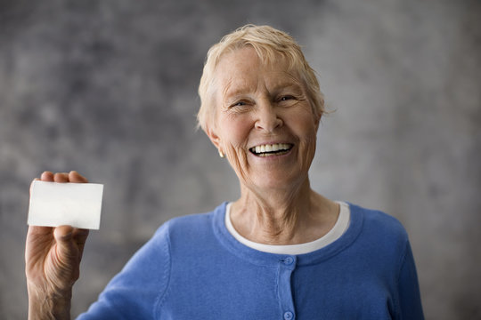 Senior woman holding up a white card.