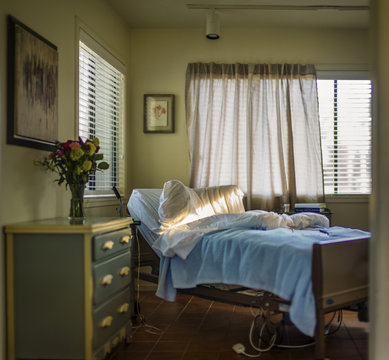 Empty hospital bed in a rest home bedroom.