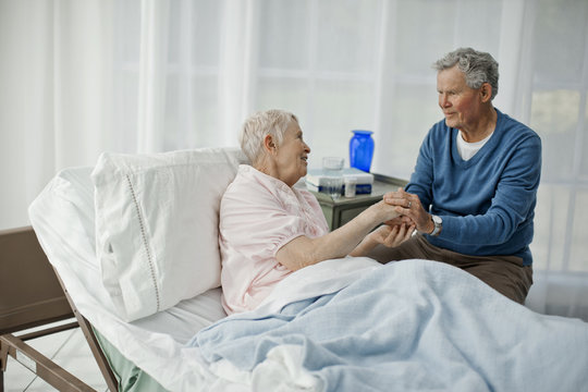 Senior man holding hands with his ailing wife.