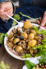 Woman hands holding backed potatoes and roasted mushrooms on salad leaves. Organic farm lunch or dinner. Raw vegan vegetarian healthy food